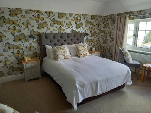 法尔茅斯特雷拉瓦酒店的卧室配有一张大白色床,墙上挂着鲜花