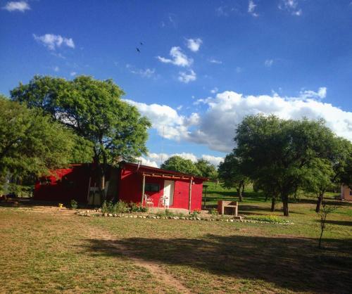 圣马科斯塞拉Cabañas Los Algarrobos的树旁田野上的红谷仓