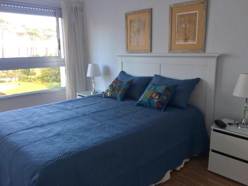 埃斯特角城Playa Mansa Parada 8的一间卧室设有蓝色的床和窗户。
