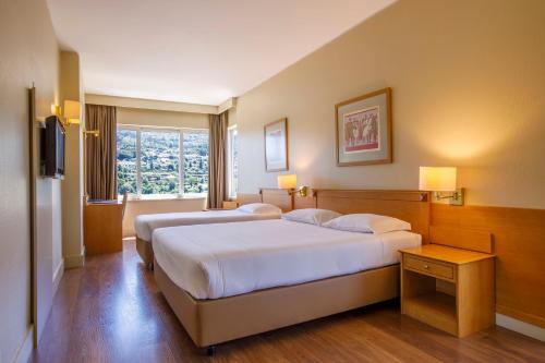吉马良斯帆迪朵酒店的酒店客房设有两张床和窗户。