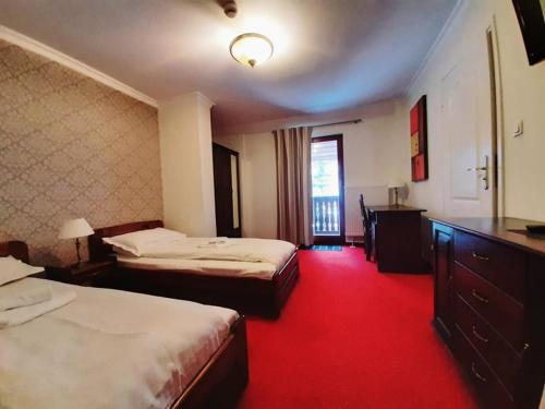 兹瓦尔东Dworek Szwajcaria的酒店客房,设有两张床,铺有红地毯。