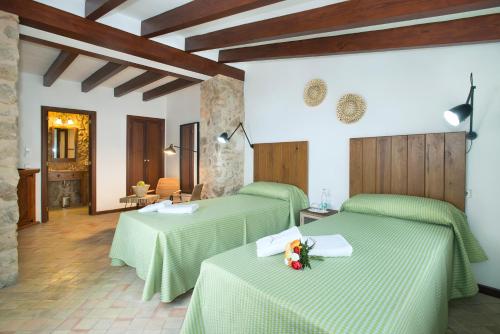 凯玛丽Petit Caimari - Turismo de interior的一间设有两张绿床的客房,床上摆放着鲜花
