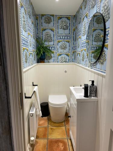 赫彻姆No33 WOODLANDS BOUTIQUE COTTAGE的浴室设有卫生间,铺有蓝色和白色瓷砖。