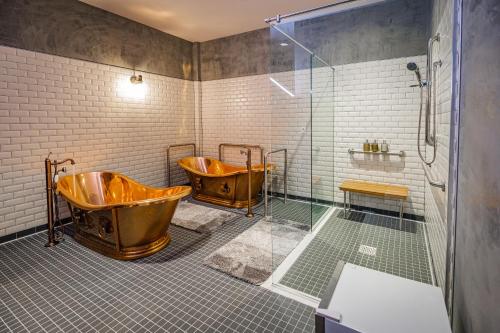 韦科Pivovar Hotel的带淋浴的浴室内的2个铜浴缸