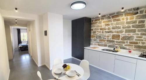 科佩尔New Apartments Škofije Ankaran的厨房配有白色橱柜和砖墙