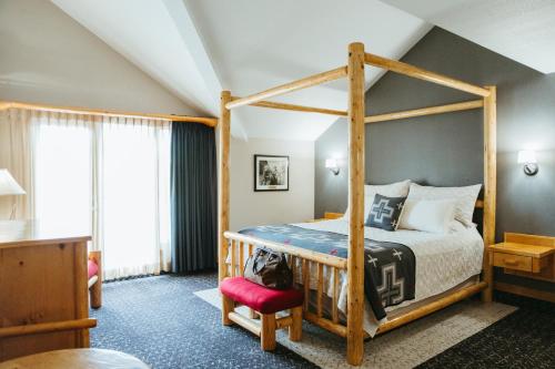 班夫Brewster Mountain Lodge的一间卧室配有一张带红色椅子的天蓬床