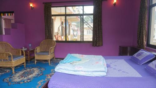 加德满都Monkey Bunky-3Monkeys Backpacker's Hostel的一间卧室设有紫色的墙壁和一张带椅子的床