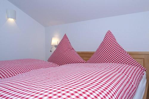 施利尔塞Ferienhaus Alpenflair bei Schliersee的红色和白色的床,配有红色和白色的格子床单