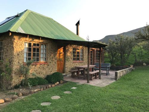 萨尼山口Sani Lodge Self-Catering Cottages Sani Pass South Africa的石头房子,配有野餐桌和长凳