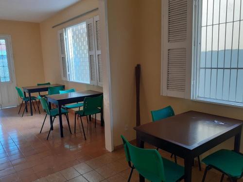 福塔莱萨Hostel Parquelândia的用餐室设有桌椅和窗户。