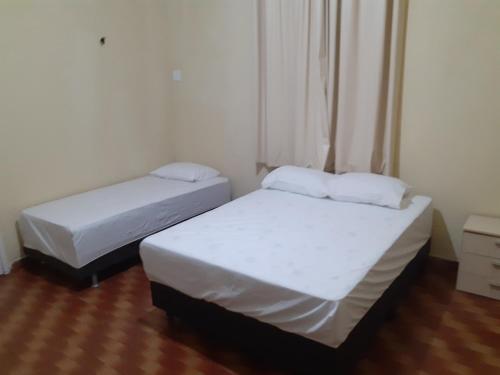 福塔莱萨Hostel Parquelândia的小客房内的两张床,配有白色床单