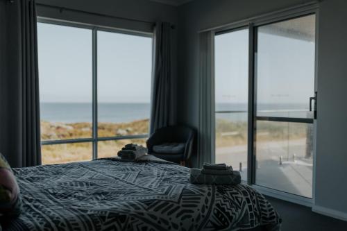 曼哲拉Beach House at SeaScapes..的一间卧室配有一张床、一把椅子和窗户。