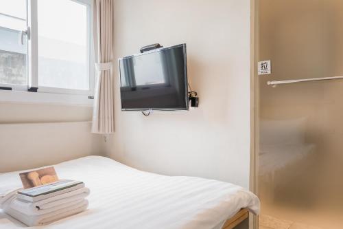 台东门廷若室旅店-铁花秀泰馆的小房间设有一张床铺,墙上配有电视