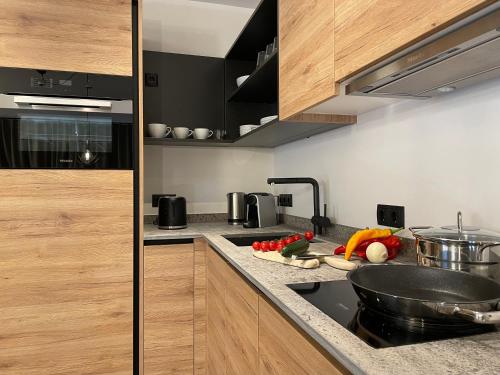 恩斯塔尔豪斯HAUSZEIT APPARTEMENTS的厨房配有木制橱柜和柜台上的蔬菜