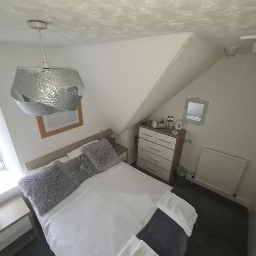 奥本Glenmoore Guest House的卧室配有白色的床和吊灯。