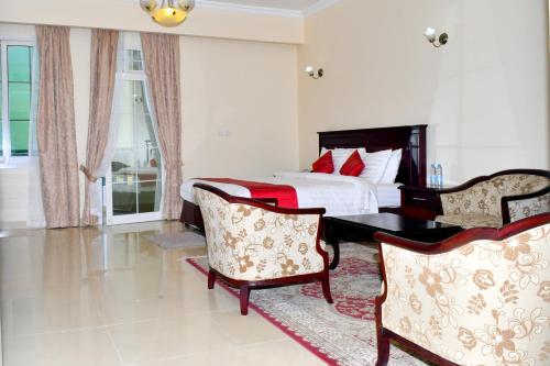 朱巴Panorama Portico Hotel, Juba的一间卧室配有一张床和两把椅子