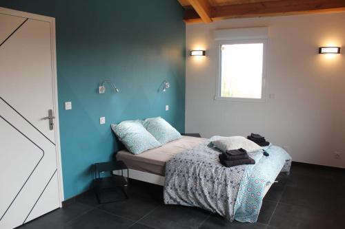 MessinhacL'AYMERAUDE的一间卧室配有一张蓝色墙壁的床和一扇窗户