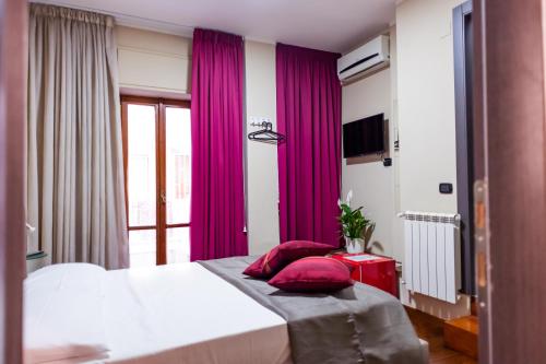 那不勒斯Royal Poerio的一间卧室配有紫色窗帘和一张带红色枕头的床