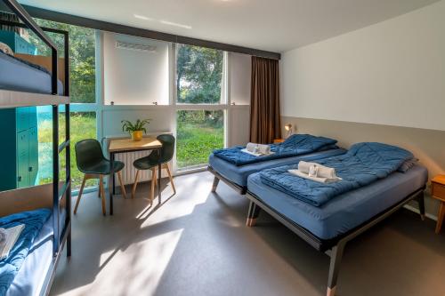 哈莱姆Stayokay Hostel Haarlem的一间卧室配有两张床和一张桌子及椅子