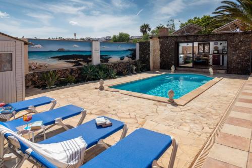 维拉韦德Villa Maravilla piscina climatizada的一个带蓝色躺椅的游泳池以及一座房子