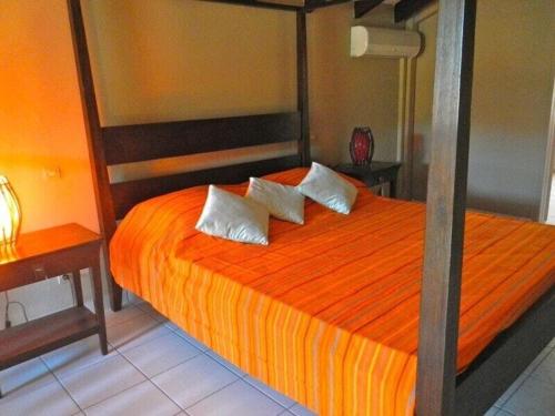 德赛duplex, 2 bedrooms, 2 couples sea view overlooking the village of DESHAIES的一间卧室配有橙色床和两个枕头