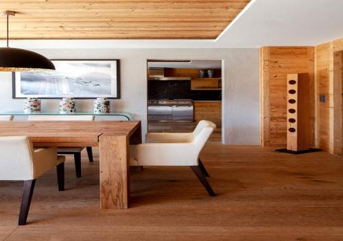 RougemontRegent Retreat by MC的一间带木桌和白色椅子的用餐室