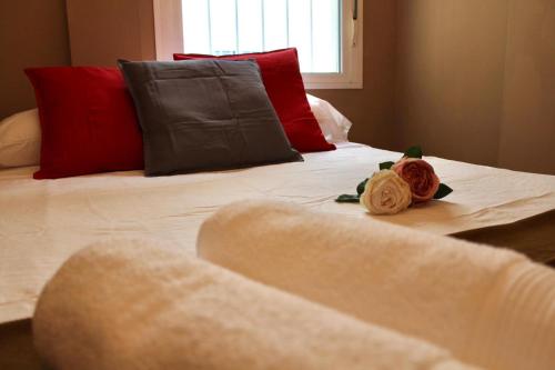 塞维利亚WISH SUITE MORERA的一张带红色枕头的白色床和两朵玫瑰花