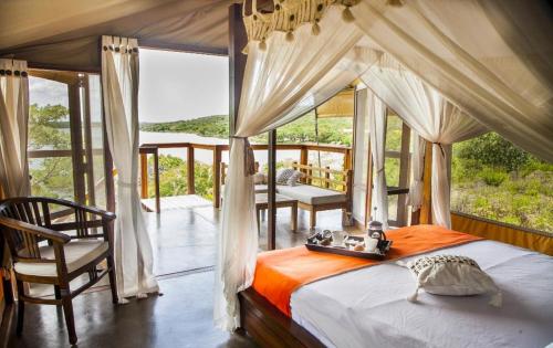 希登盖莱Naara Eco Lodge & Spa的一间卧室设有一张天蓬床和一个阳台