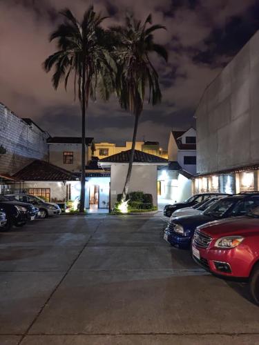 昆卡Hotel Calle Angosta的棕榈树和汽车的夜间停车场