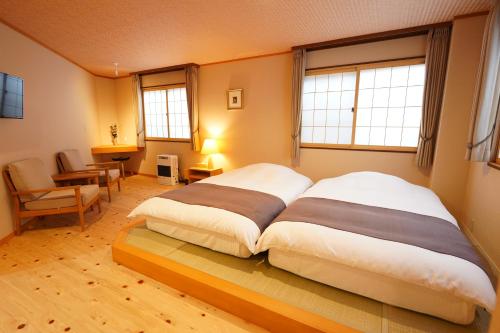 草津索美安日式旅馆的一张大床,位于带两个窗户的房间