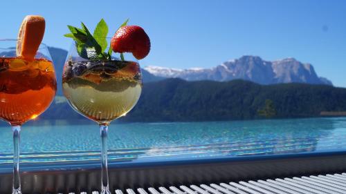 拉伊翁Hotel Andechserhof & Mountain Sky的坐在桌子上一边欣赏水景一边享用2杯鸡尾酒