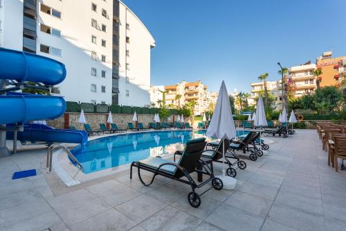 阿拉尼亚Kaila City Hotel的一座带躺椅和遮阳伞的游泳池位于一座大楼旁