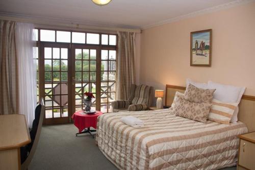 LeribeMountain View Hotel - Lesotho的一间卧室配有一张床、一张书桌和一个窗户。