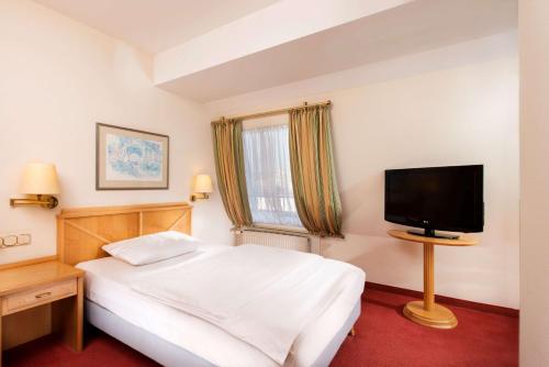 科隆科隆市中心文登萃浦酒店的一间卧室配有一张床和一台平面电视