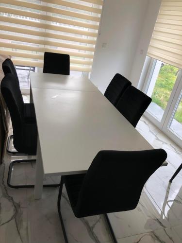 上阿斯巴赫Luxusvilla Neubau 2的客房内的一张带黑椅子的白色桌子