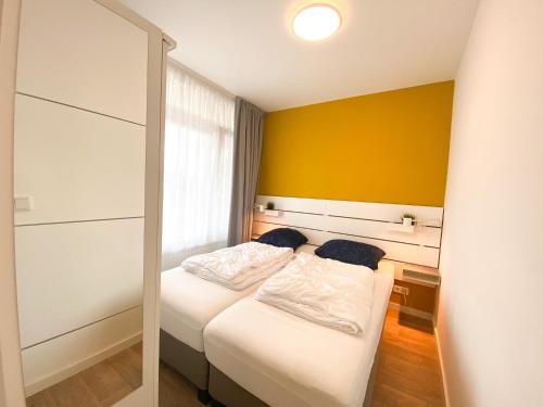 韦斯特卡佩勒Vakantieappartement Westkapelle WE07的一间卧室设有两张床和黄色的墙壁