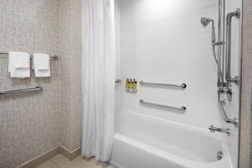 皇后区Holiday Inn Express & Suites Woodside LaGuardia Airport的浴室配有白色浴缸和淋浴。