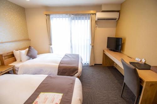 京都Stay SAKURA Kyoto Shijo Karasuma的酒店客房设有两张床和一台平面电视。