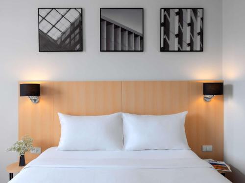 曼谷宜必思曼谷素坤逸 4 酒店的卧室配有一张白色床,墙上挂有4张照片