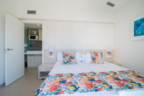 马斯帕洛马斯Hotel LIVVO Dunagolf Suites的卧室配有一张带彩色枕头的大型白色床。