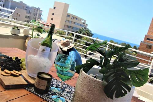 德班Luxury Apartment in Umhlanga Rocks的阳台上的桌子上摆放着一瓶葡萄酒和玻璃杯
