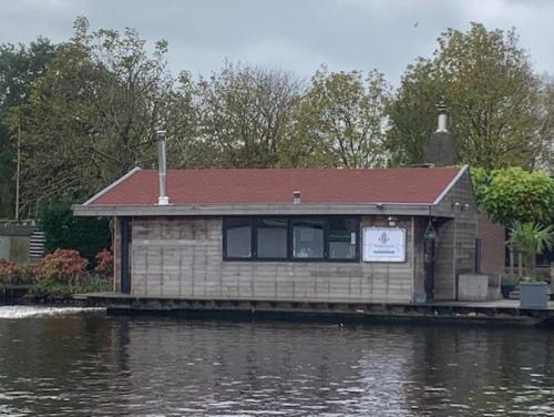 莱茵河畔阿尔芬Aangenaam op de Rijn, woonboot, inclusief privé sauna的水体旁的码头上的房子