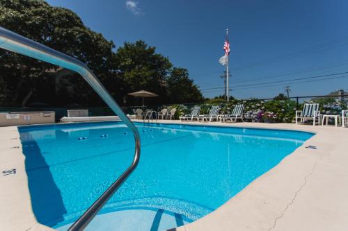 West Harwich海滩微风汽车旅馆的一个带蓝色水和白色椅子的游泳池