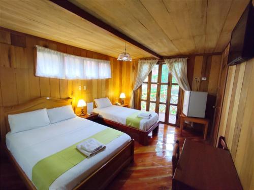 弗朗西斯科德奥雷利亚纳港Hotel El Auca的一间卧室配有两张床和电视。