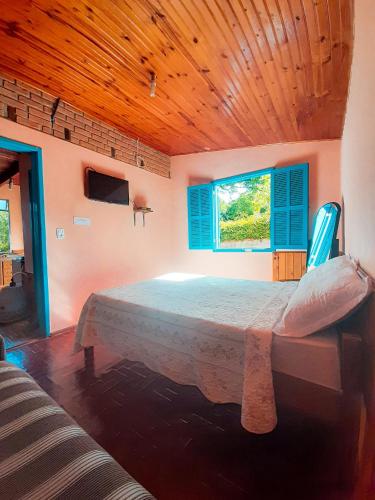 康塞高伊比蒂波卡Chalé da Léia的一间卧室设有一张带木制天花板的大床