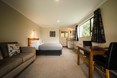因弗卡吉尔Invercargill Holiday Park & Motels的一间卧室配有一张床、一张沙发和一张桌子