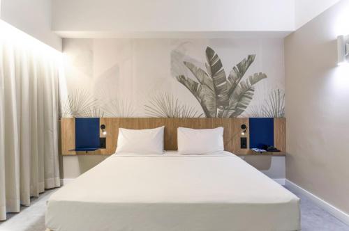 萨尔瓦多Novotel Salvador Rio Vermelho的一间卧室配有一张带白色床单的大床