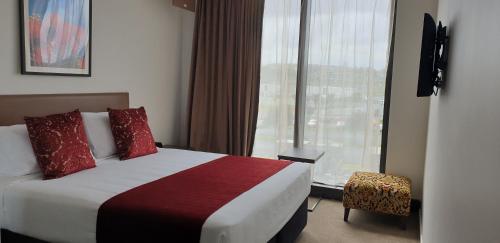 奥克兰Ramada Suites by Wyndham Manukau的酒店客房设有一张床和一个大窗户