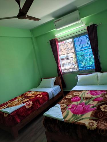 博卡拉Harry Guest House & Restaurant的配有两张床的客房,设有绿色的墙壁和窗户
