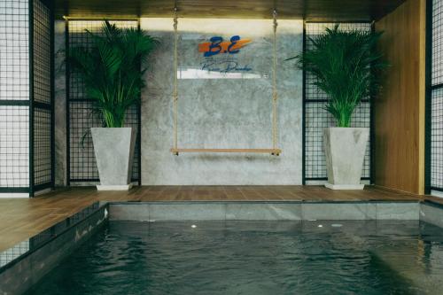 芭东海滩BE Rendez Vous Hotel的一个室内种植了两株盆栽植物的游泳池